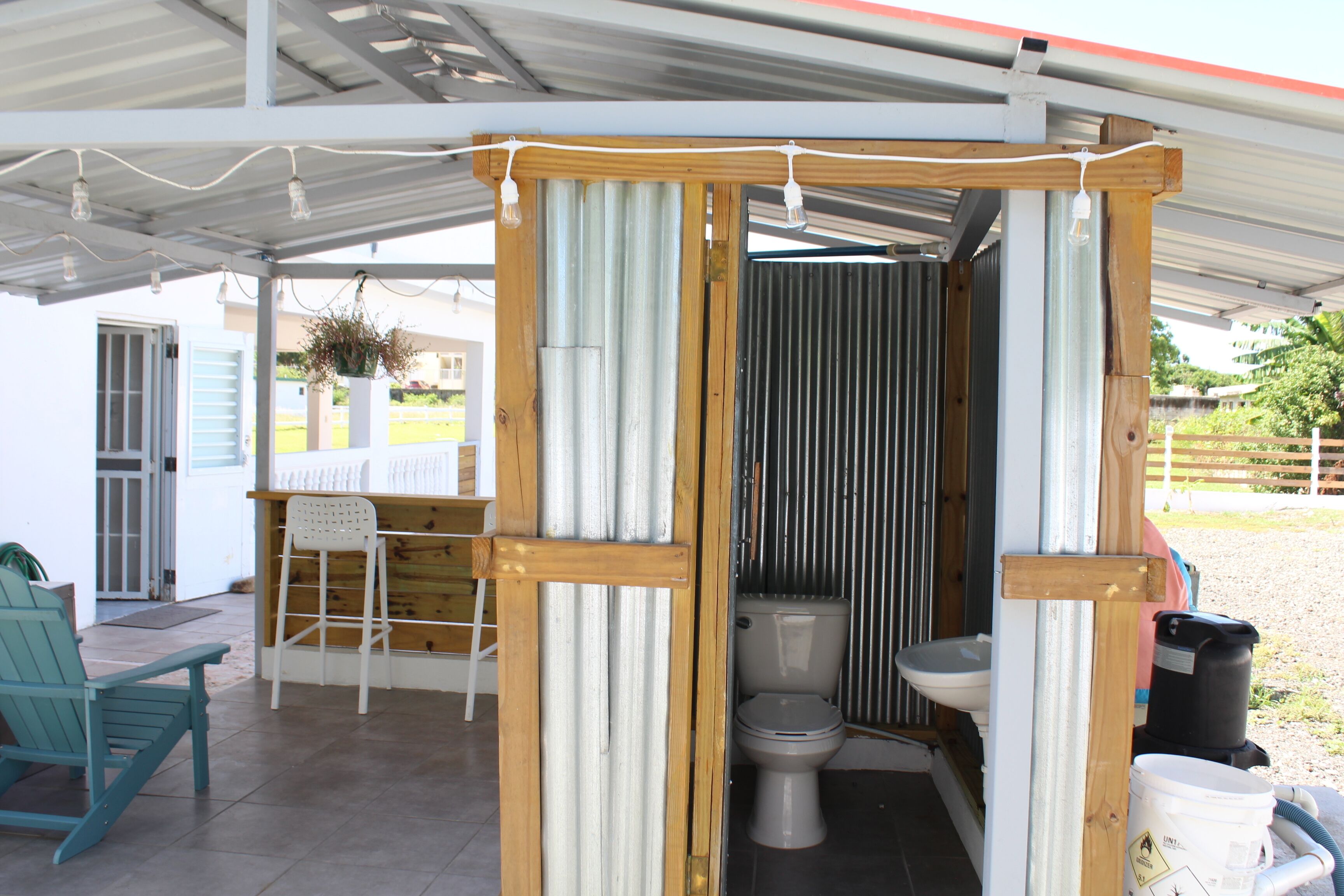 Een kleine, afgesloten buitentuin met een toilet, wastafel en een stoel.