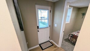 A hallway with a wooden floor, a white door with a window, and a small rug. - Lakefront Home with Sunsets, Dock, and Deck!  Dogs Stay Free! (Delton)