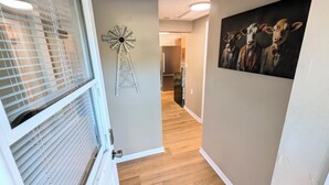 A hallway with a wooden floor, a windmill decoration, and a painting of cows on the wall. - Lakefront Home with Sunsets, Dock, and Deck!  Dogs Stay Free! (Delton)