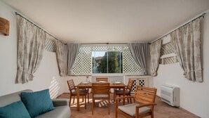 A cozy dining area with a table and chairs, a sofa, and a window with curtains. - Sweet Mavy Incantevole Dimora by Wonderful Italy (Olbia)