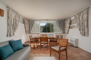 A cozy dining area with a table and chairs, a sofa, and a window with curtains.