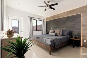 Un dormitori modern amb un llit, un ventilador de sostre, una finestra amb cortines i vista cap a l'exterior.