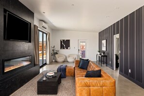 Un salon moderne avec une cheminée, un canapé en cuir et un téléviseur à écran plat.