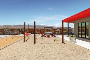 Une terrasse extérieure avec un hamac, un espace salon et une vue sur les montagnes.
