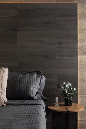 Cozy king bedroom detail with plush quilted bedding, a warm wood accent wall