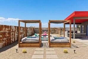 Two queen-size canopy day beds poolside for shaded lounging