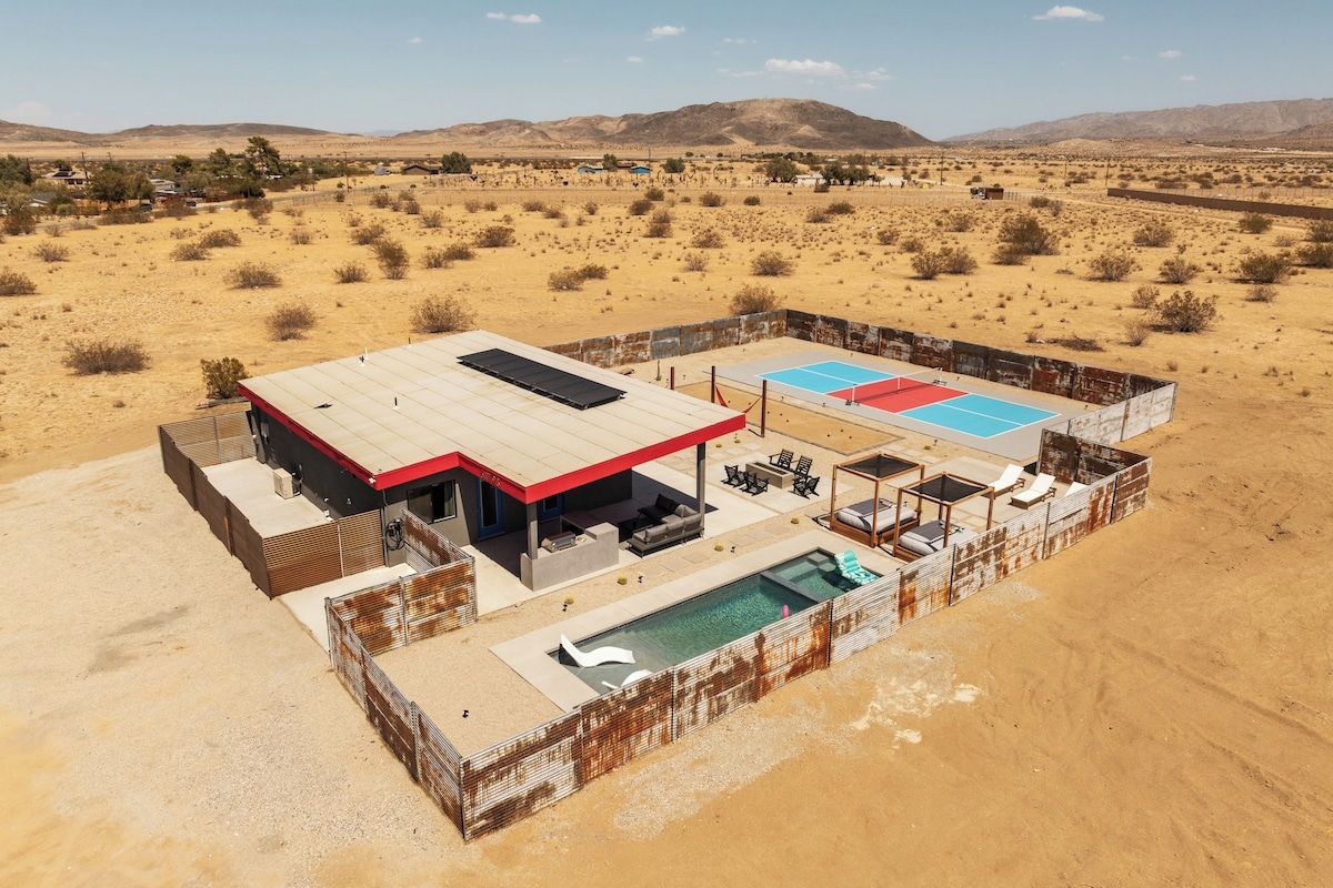 A desert resort with a pool, outdoor seating, and a view of the surrounding landscape.