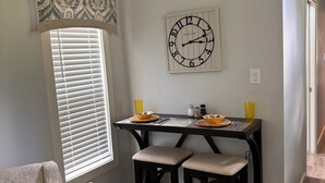 Un comedor con una mesa de madera, dos sillas y un reloj de pared.