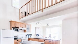 A spacious kitchen with wooden cabinets, a central island, and a wooden staircase. - Oceanside beautiful vacation property! (Lewisporte)