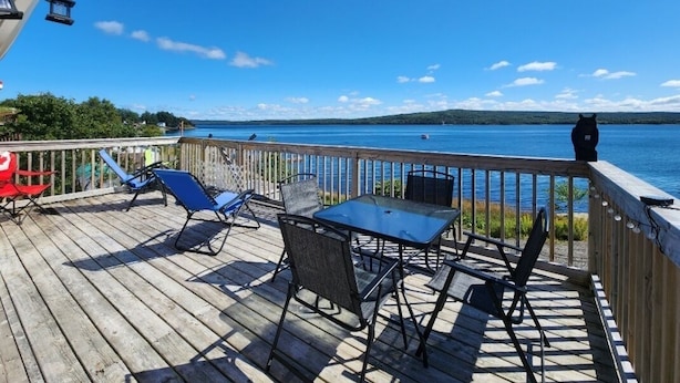 A wooden deck with outdoor furniture, overlooking a body of water and distant land. - Oceanside beautiful vacation property! (Lewisporte)