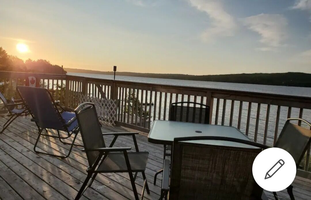 Terraza con mobiliario exterior y vista a un cuerpo de agua al atardecer.