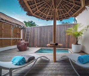 A wooden deck with a pool, lounge chairs, a hot tub, and a thatched umbrella. - Maison Clementine (Fort-de-France)
