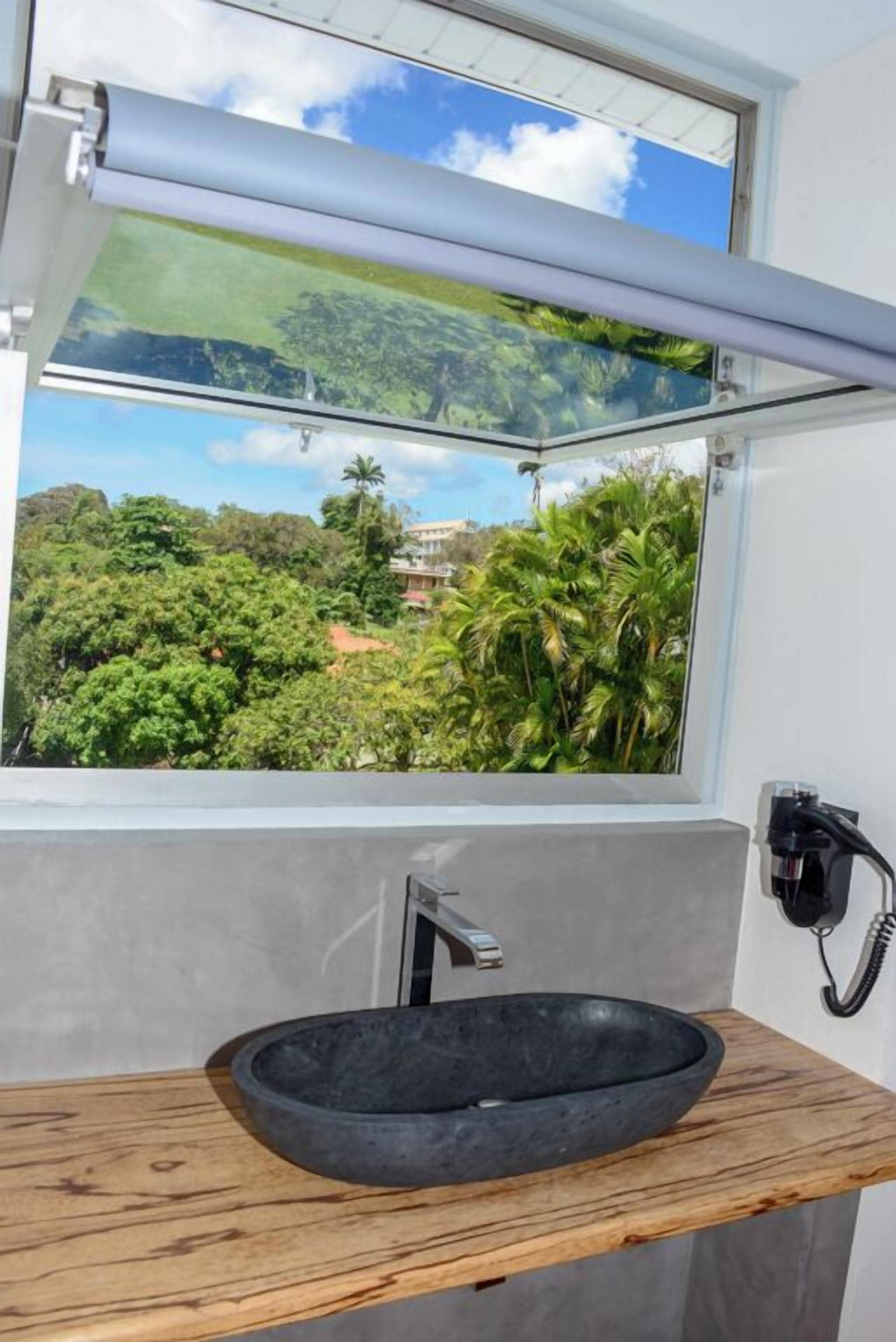 A bathroom with a large window, a black basin, and a wooden countertop.