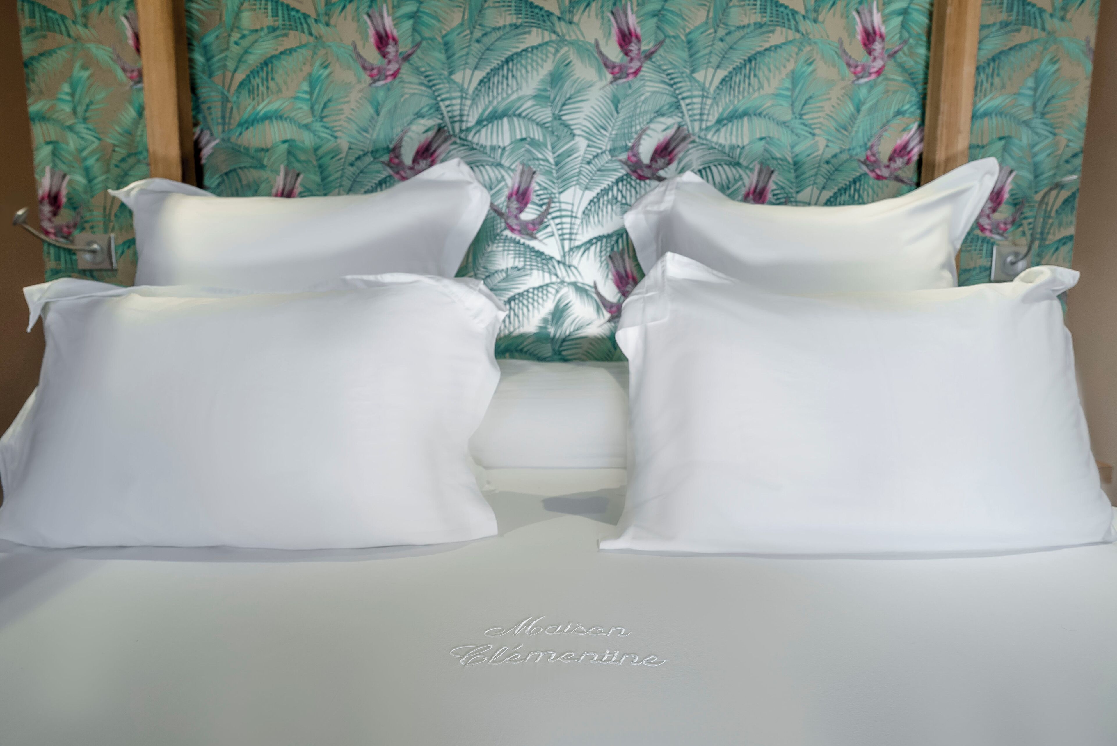 A bed with white pillows and a floral-patterned headboard.