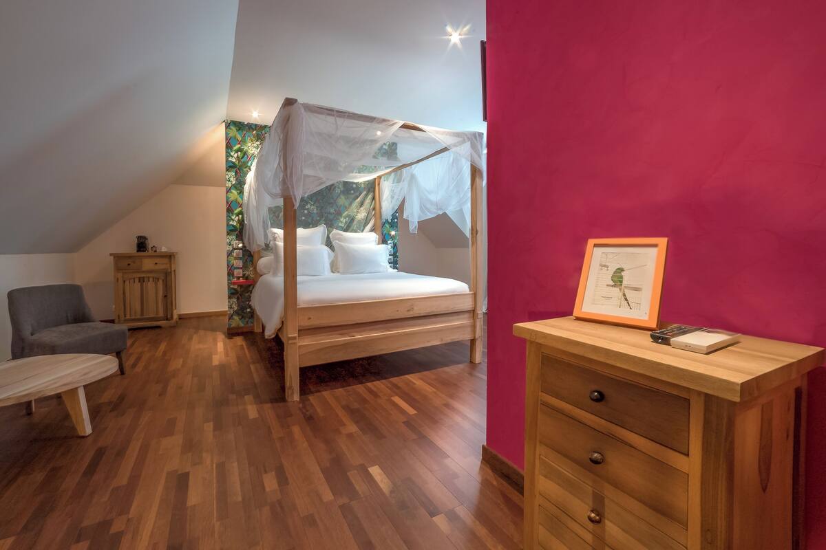 A bedroom with a wooden bed, a chair, a small table, and a dresser.