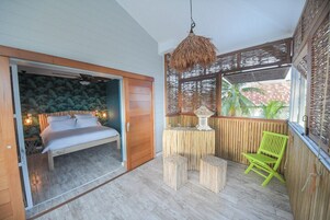 Une chambre à coucher avec un lit, une petite table avec des tabourets, une chaise et un luminaire suspendu.