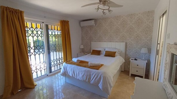 A bedroom with a bed, a nightstand, a ceiling fan, and a window with curtains.