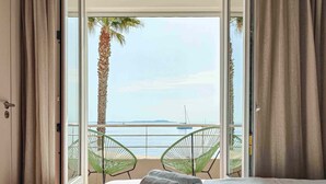 Una camera d'albergo con un letto grande, due sedie vicino alla finestra e vista sul mare.