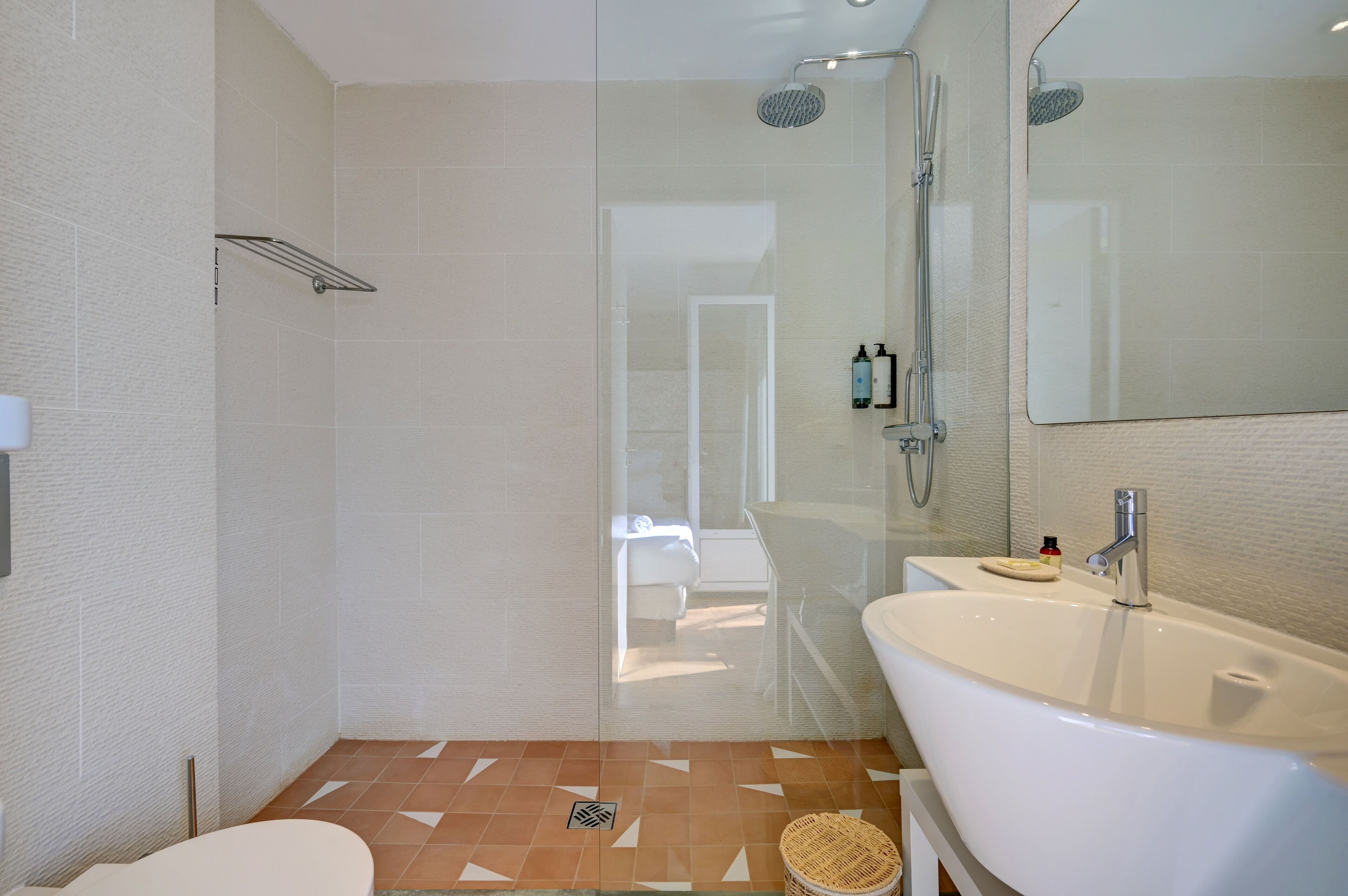 Un baño moderno con ducha acristalada, bañera independiente y un espejo grande.