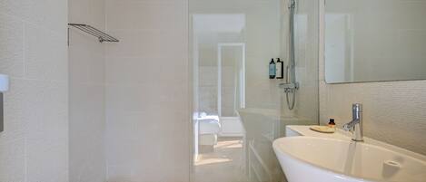 Un baño moderno con ducha acristalada, bañera independiente y un espejo grande.