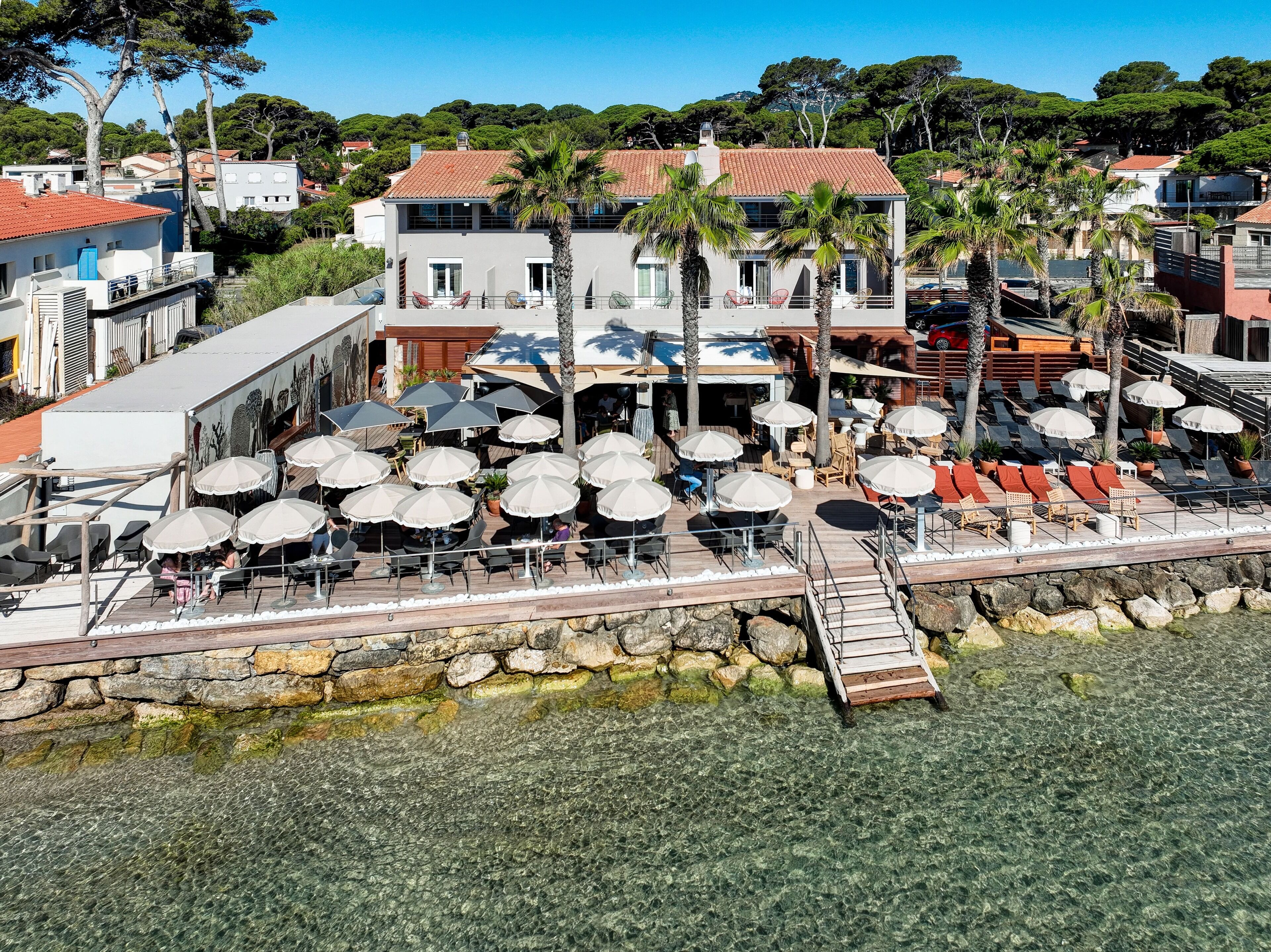 Une station balnéaire dotée d’une terrasse, de palmiers et offrant une vue dégagée sur la mer.