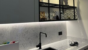 Eine moderne Küche mit Spüle, einer Arbeitsplatte mit Laptop und Ladegerät sowie einer Wanddekoration mit einer Skulptur mit Flügeln.