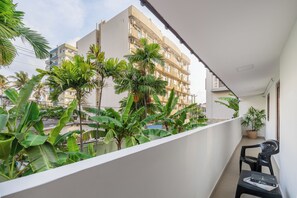 A balcony with a view of a building, potted plants, and a chair. - The Islands Breeze Villa (Dehiwala-Mount Lavinia)