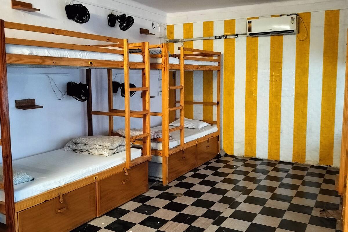 A room with bunk beds, a checkered floor, and a striped wall.