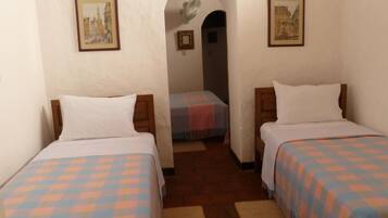 Una habitación con dos camas, cada una con colcha a cuadros, una mesita y un cuadro en la pared.