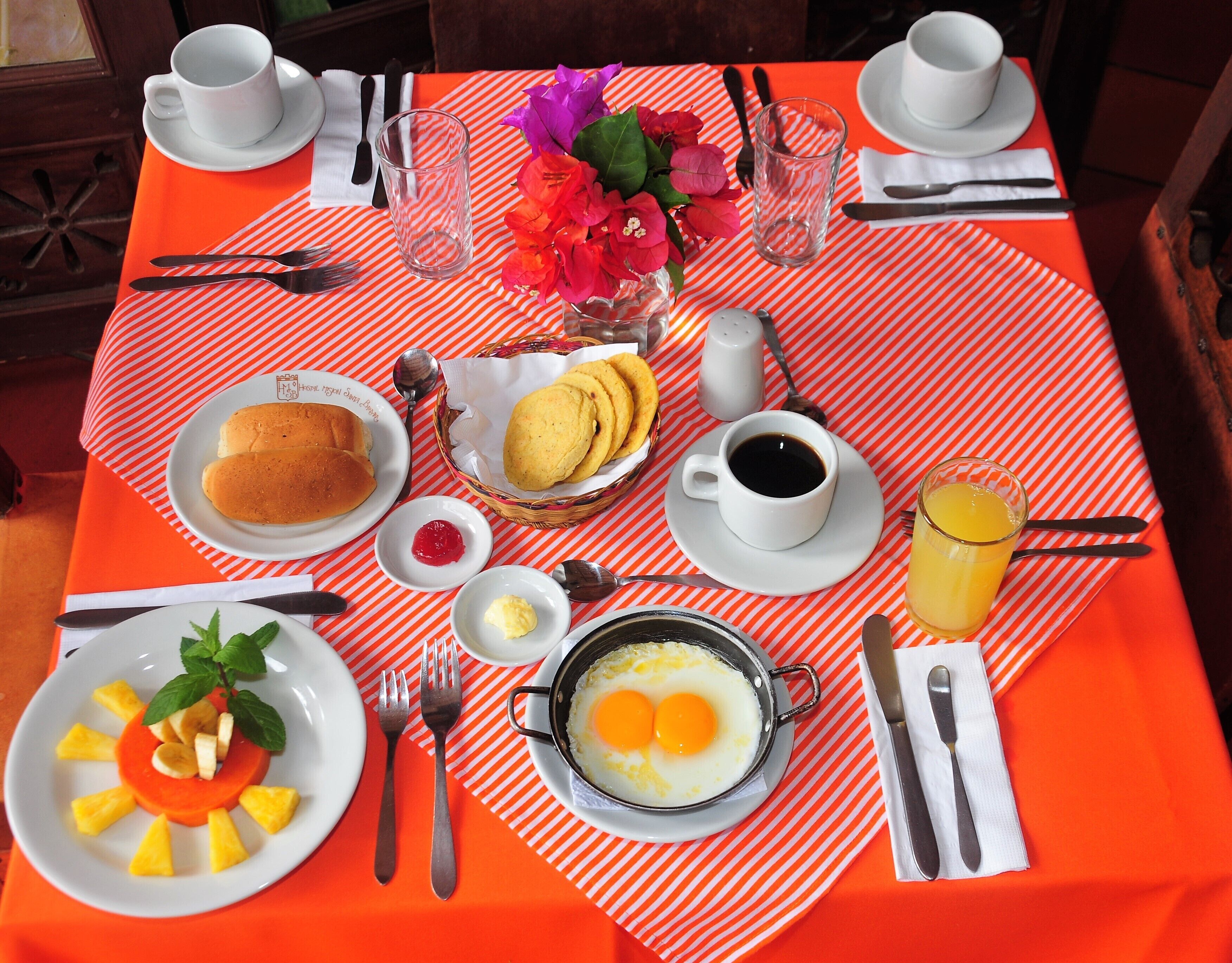 Ett frukostbord med tallrikar fulla av mat, en kopp kaffe och ett glas apelsinjuice.