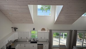 A modern kitchen with white cabinets, a large window, and a view of the outdoors.