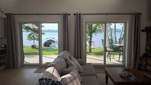 A living room with a sofa, a coffee table, and a view of a lake with a dock and boat.