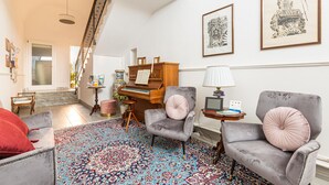 A spacious living room with a grand piano, two armchairs, a patterned rug, and a staircase leading to an upper floor. - Holiday Studio at Dimora Le Tre Muse Charming Guesthouse in Lecce (Lecce)