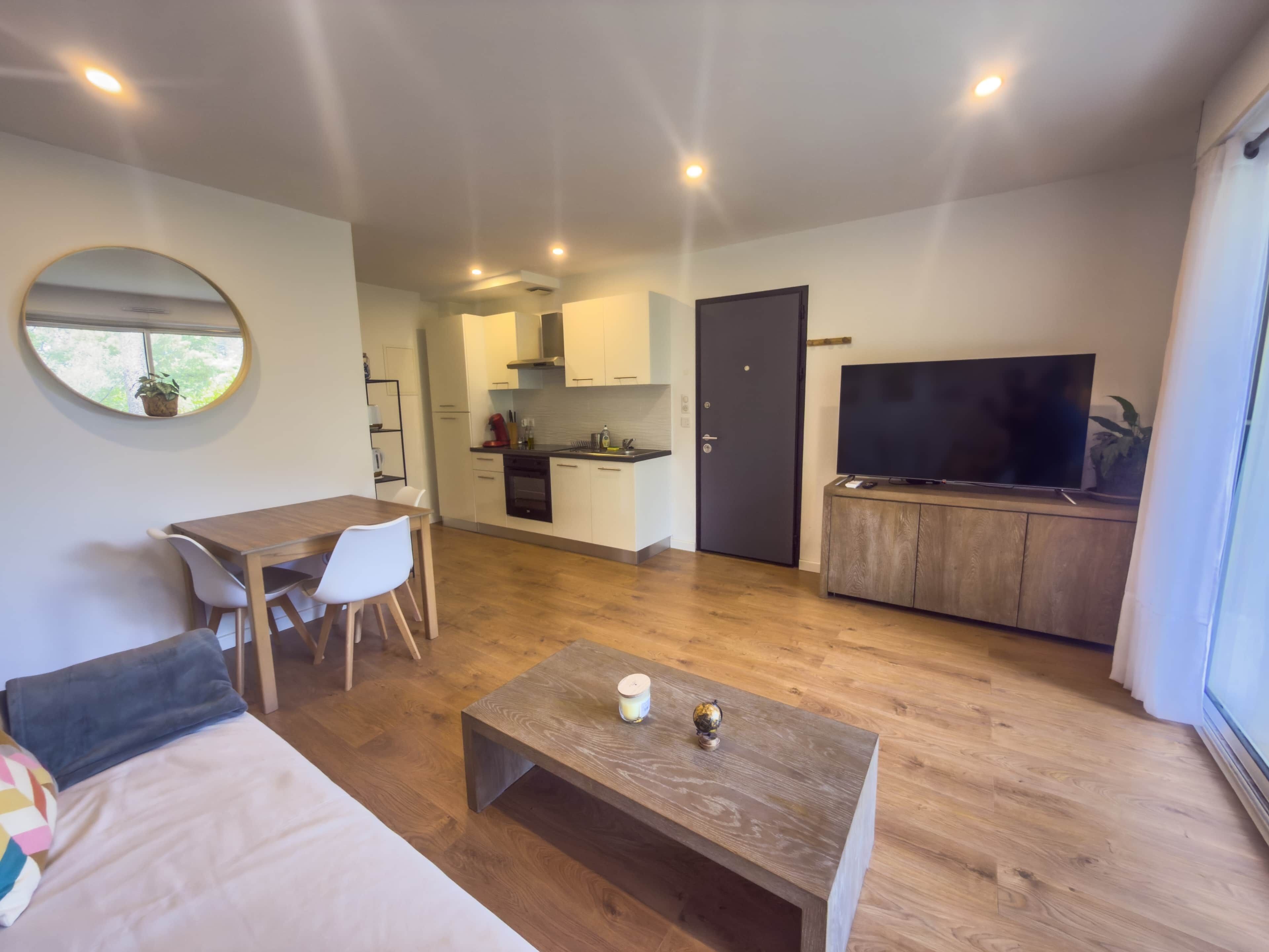 A modern living space with a dining area, kitchen, and a TV area.