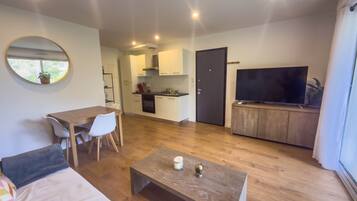 A modern living space with a dining area, kitchen, and a TV area.
