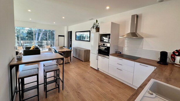A modern kitchen with wooden flooring, white cabinetry, and a built-in oven. - To complete (Saint-Clément-de-Rivière)