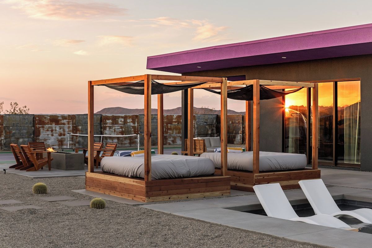 A rooftop terrace with wooden beds, lounge chairs, and a fire pit.