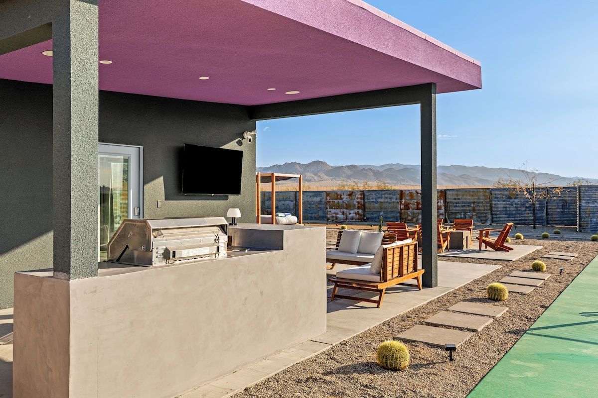 An outdoor patio with a barbecue area, seating, and a view of mountains.
