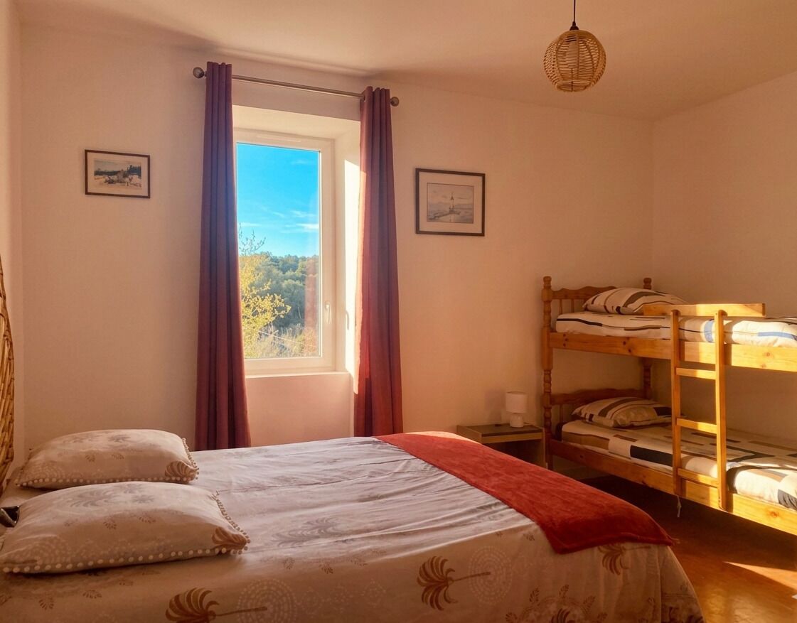 A bedroom with a single bed, a bunk bed, a window with curtains, and a hanging light fixture.