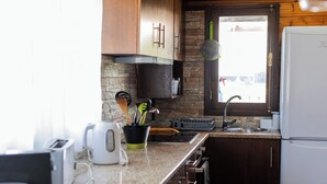 A kitchen with wooden cabinets, a granite countertop, a built-in oven, and a window with a view. - Gothes Chalet Javier!! (Ponte de Vagos)