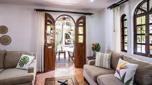 Un salon avec deux canapés, une table basse et une vue sur un patio extérieur, accessible par une porte ouverte.