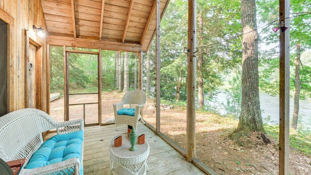 Eine Holzterrasse mit Korbmöbeln und Blick ins Waldgebiet.