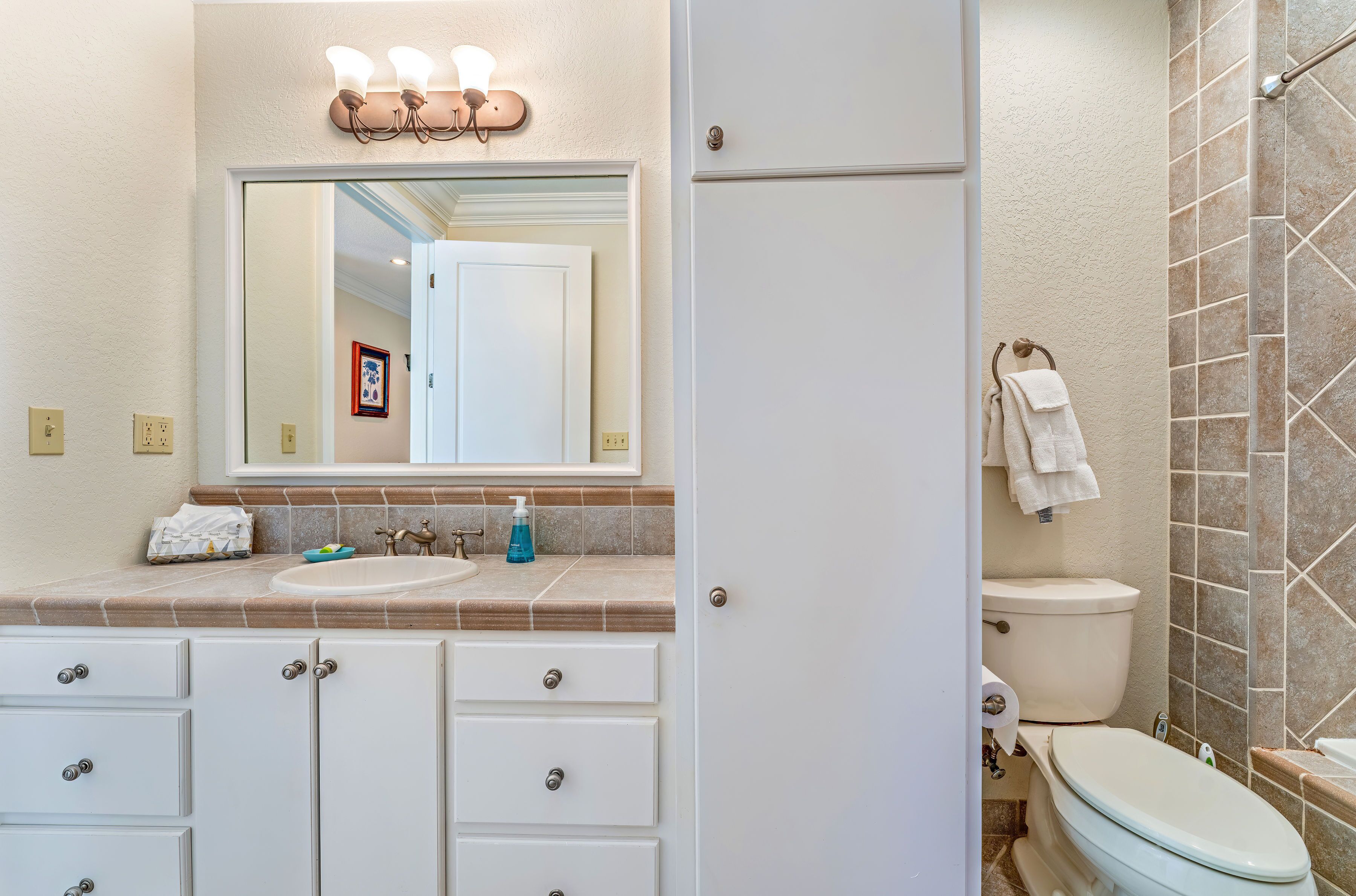 Une salle de bain comprenant un lavabo, un miroir, un meuble-lavabo, des toilettes et un espace douche.