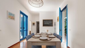 Une salle à manger avec une table rectangulaire dressée pour six personnes, entourée de chaises bleues.