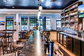 A bar area with a long counter, stools, and a variety of bottles and glasses.