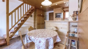 Un intérieur en bois avec une table ronde, un escalier en bois et un coin cuisine.