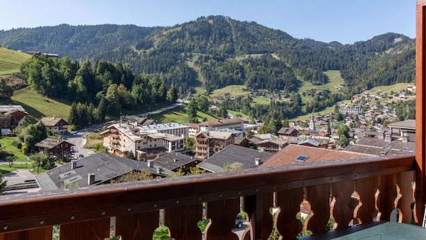 Une ville dont les bâtiments sont entourés de collines boisées.