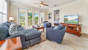 A living room with a sofa, armchair, TV, and ceiling fan. - Pickleball and Pool Paradise 2b/2b (Carrabelle)