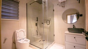 A modern bathroom with a glass-enclosed shower, a white toilet, and a vanity with a sink. - BnJ Benin City Oasis - Spacious 3BR Apartment (Benin City)