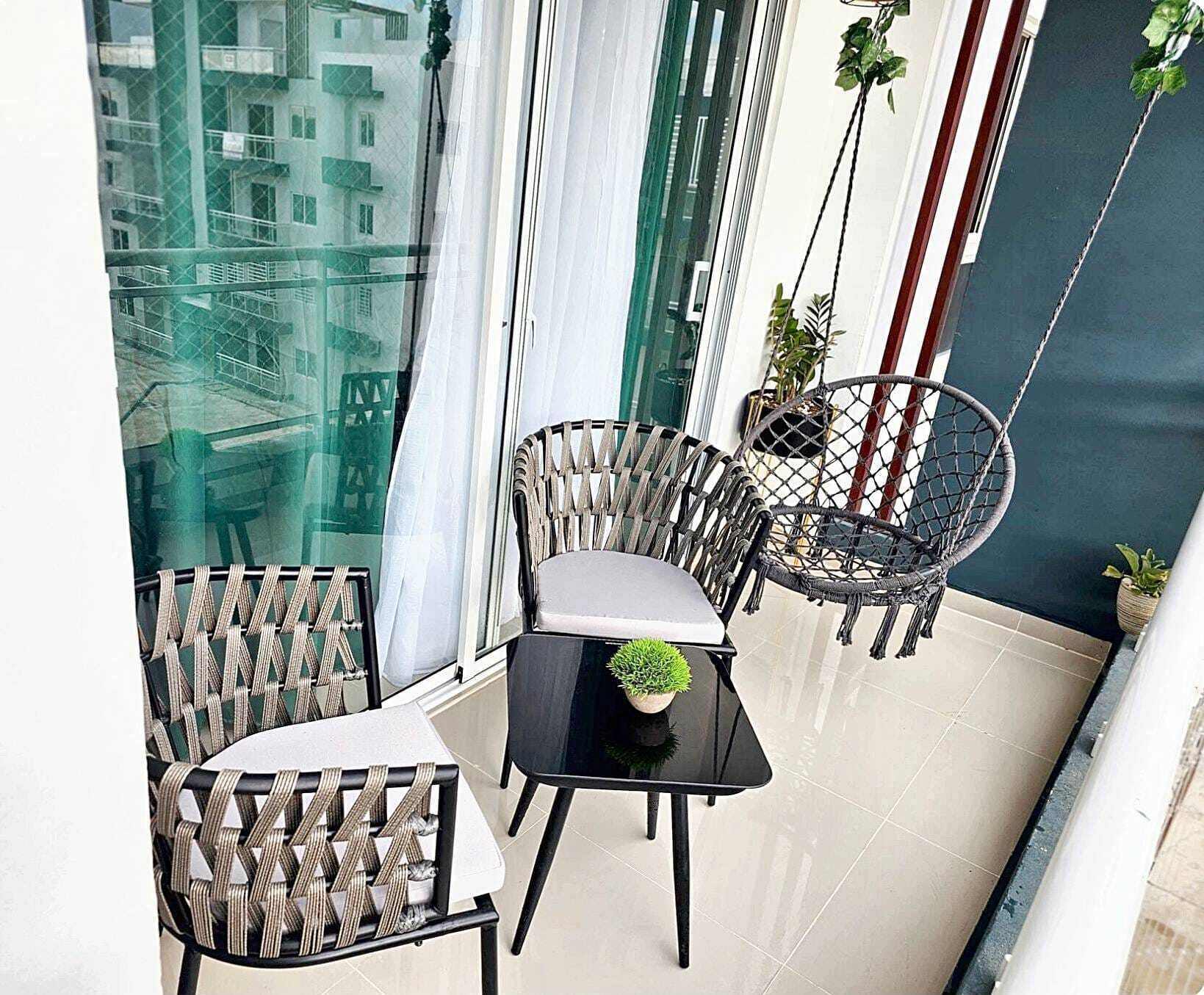 Ein Balkon mit zwei Korbstühlen, einem kleinen Tisch und einem Blumentopf.